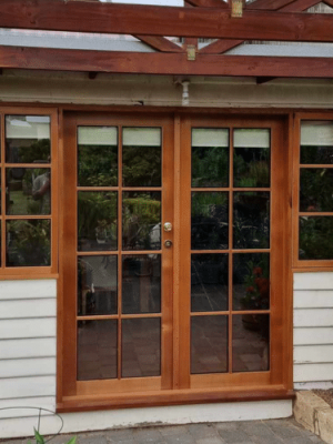 Timber French doors on a weather board white house